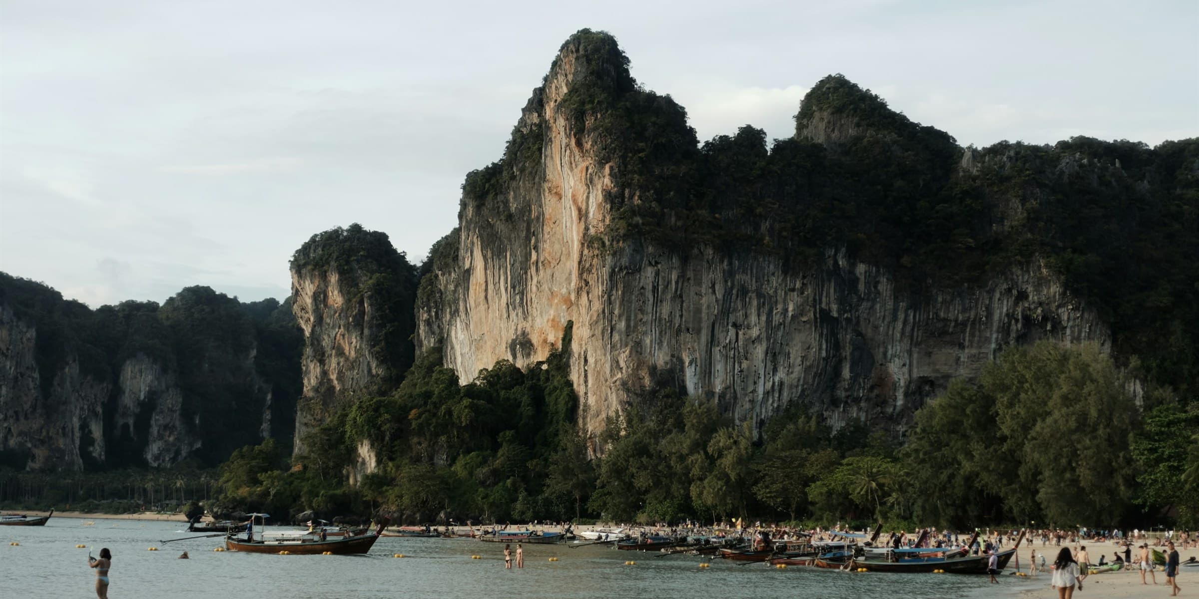 Longtail boats at Railay Beach below limestone cliffs in Krabi